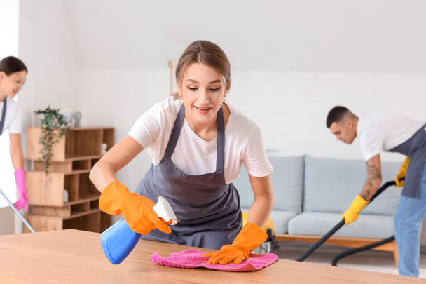 Female janitor cleaning table in room - 写真・画像