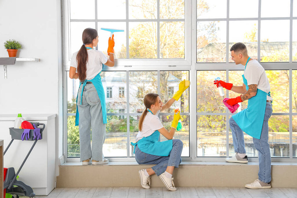 Team van jonge conciërges schoonmaken raam in keuken, achteraanzicht - Foto, afbeelding