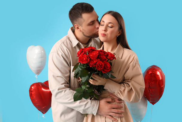 Krásný pár s kyticí růží a balónky ve tvaru srdce na modrém pozadí. Valentýnská oslava - Fotografie, Obrázek