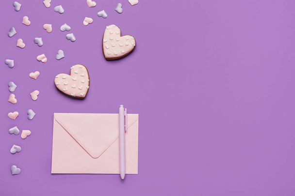 Słodkie ciasteczka w kształcie serca i koperta na fioletowym tle. Walentynki święto - Zdjęcie, obraz