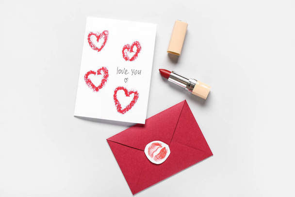 Tarjeta de felicitación, sobre y lápiz labial sobre fondo gris. Celebración de San Valentín - Foto, Imagen