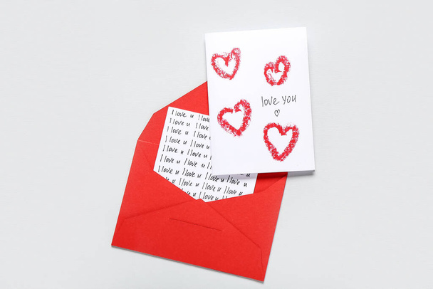 Sobre rojo y tarjeta con texto LOVE YOU sobre fondo gris. Celebración de San Valentín - Foto, Imagen