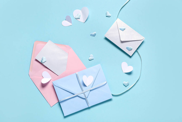 Composición con sobres, tarjeta en blanco y corazones sobre fondo de color. Celebración de San Valentín - Foto, Imagen