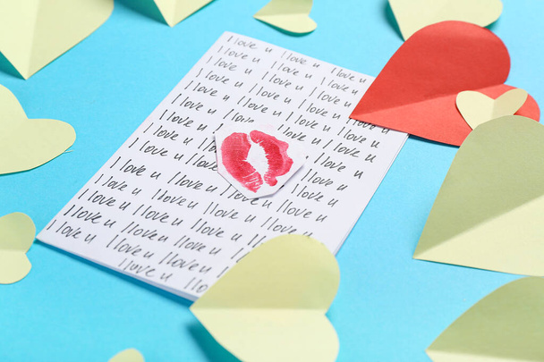 Kompozycja z kartką z życzeniami, papierowymi sercami i śladami pocałunku szminki na tle koloru, zbliżenie. Święto Walentynek - Zdjęcie, obraz