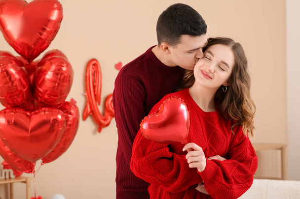 Boldog fiatal pár otthon szív alakú léggömbökkel otthon Valentin-napon - Fotó, kép