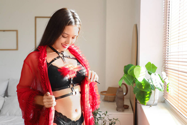Sexy jeune femme asiatique avec bâton de plume dans la chambre. Fête de la Saint-Valentin - Photo, image