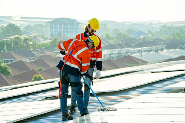 Ingenieros profesionales revisando el techo solar en la azotea de fábrica bajo la luz solar. Ingenieros con trabajo de servicio de energía eléctrica renovable - Foto, Imagen