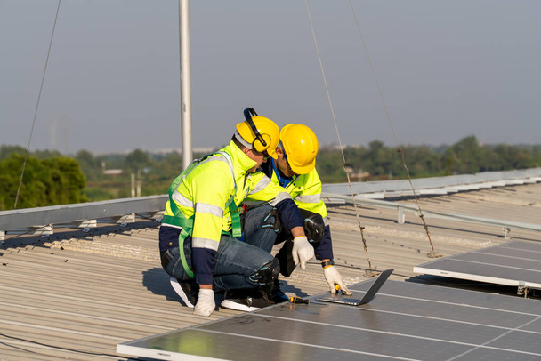 Ingegneri professionisti che controllano il tetto solare sul tetto della fabbrica sotto la luce solare. Ingegneri che svolgono attività di servizio di energia elettrica rinnovabile - Foto, immagini