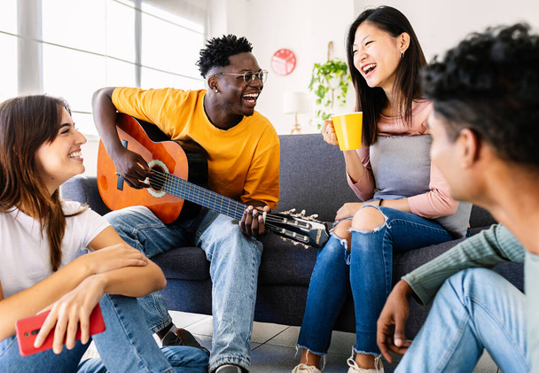 Diverse vriendengroepen genieten van tijd samen thuis. Millennial college studenten opknoping rond in de woonkamer op gedeelde flat. Jeugdgemeenschap en vriendschapsconcept. - Foto, afbeelding