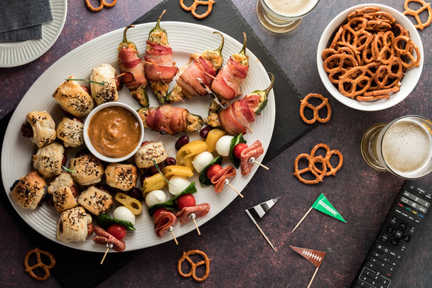 Top down view of a platter of game day appetizers with pretzels and beer. - Photo, Image