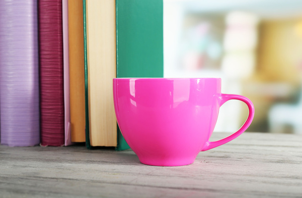 Color cup of drink with books on wooden surface and light background - Valokuva, kuva