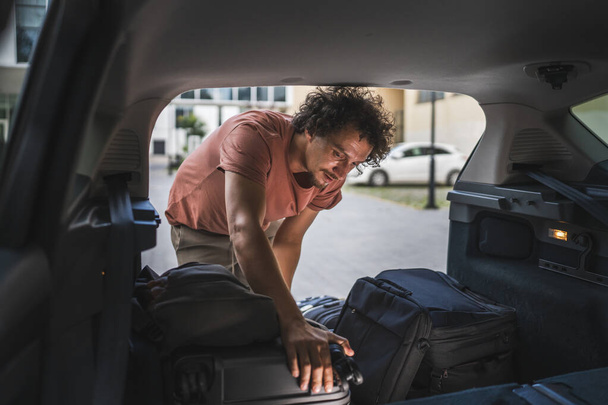 Один дорослий чоловік подорожує концепцією чоловіки беруть речі ззаду або кладуть у багажник автомобіля під час переїзду або прибуття до місця призначення справжні люди копіюють простір - Фото, зображення