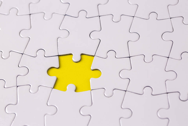 Missing jigsaw puzzle pieces. Business concept. Fragment of a folded white jigsaw puzzle and a pile of uncombed puzzle elements against - Foto, imagen