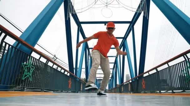 熟練したヒップスターは,スタイリッシュな布を着用しながら,低角度のカメラで橋で足を踏みます. プロのストレスダンサー練習ブレイクダンス. 現代のライフスタイル。 アウトドアスポーツ 2024。 スプライトリー. - 映像、動画