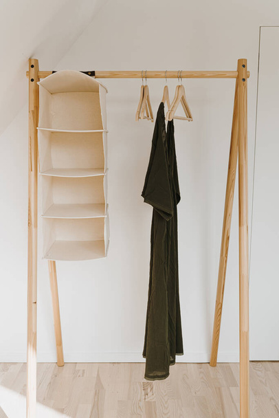 Kleiderschrank für Damenmode. Stilvolles weibliches Abendkleid auf Bodenbügel über weißer Wand. Minimalistische Mode Blog, Online-Shop, Online-Shop, Mode-Magazin Hintergrund - Foto, Bild
