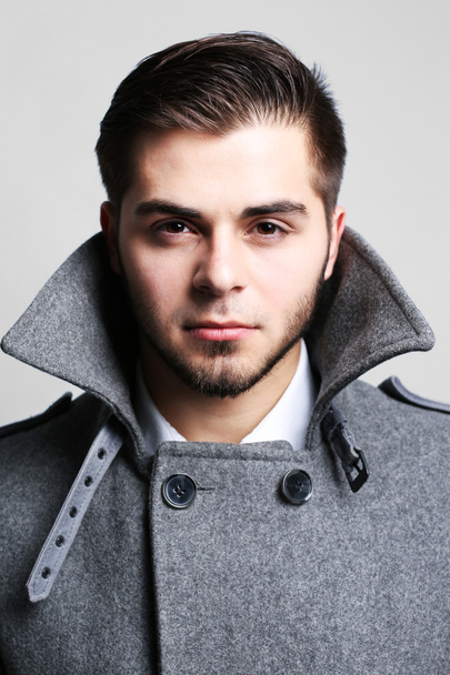 Young man in coat on gray background - Photo, image