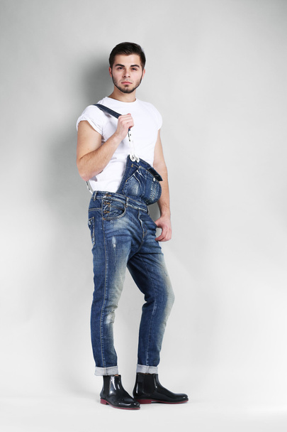 Man in jeans coveralls on gray background - Fotografie, Obrázek