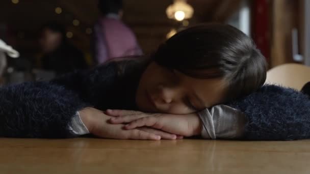 Een depressief kind met hoofd op tafel, diep bedroefd, close-up van een melancholisch 8-jarig kind in restaurant - Video