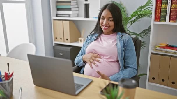 Expecting young business woman, smiling and touching belly while enjoying a successful video call at the office - Footage, Video
