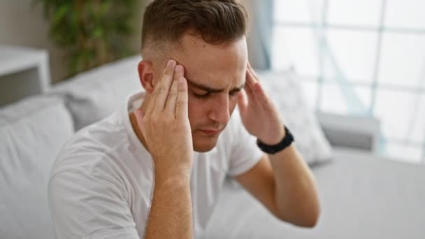 Молодий чоловік відчуває головний біль або стрес в сучасній домашній обстановці. - Кадри, відео