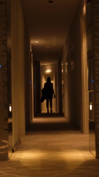 una joven con un vestido negro corto entra en su habitación de hotel - Imágenes, Vídeo