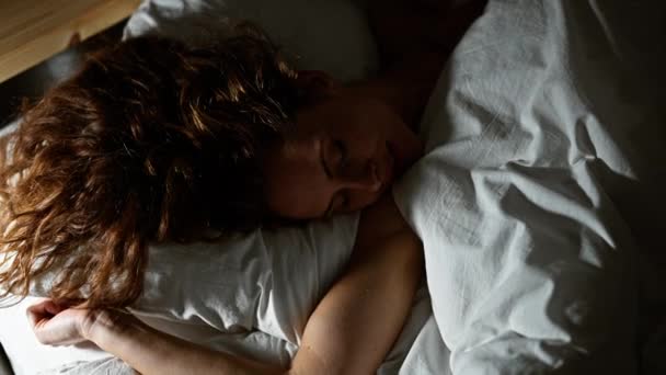 Een jonge vrouw rustig slapen in een gezellige slaapkamer, markeren rust en ontspanning. - Video
