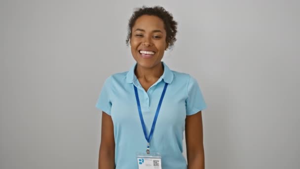 Χαρούμενη, νεαρή Αφρικάνα Αμερικανίδα που στέκεται με αυτοπεποίθηση με την ταυτότητά της, αποπνέοντας θετικότητα με ένα πλατύ χαμόγελο σε ένα απομονωμένο λευκό φόντο - Πλάνα, βίντεο