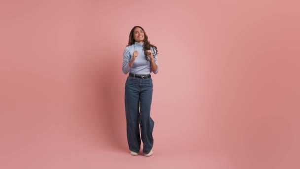 Koko kehon pituus aikuinen kolumbialainen nainen 30s pukeutuu rento vaatteita tanssia tavallinen pastelli vaaleanpunainen tausta studio - Materiaali, video