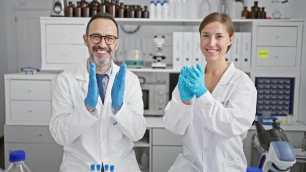 Dos científicos sonrientes aplaudiendo aplaudiendo, celebrando un gran avance de la investigación en su laboratorio - Metraje, vídeo