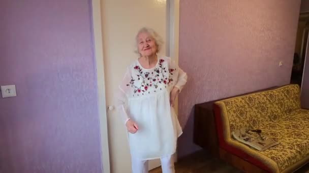 Szczęśliwy uśmiech śmieszne starsza kobieta w białej sukience taniec w domu - Materiał filmowy, wideo