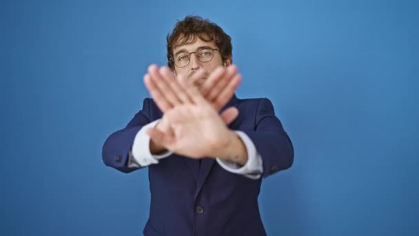 Angry young man in business suit crosses arms, palms signifying rejection. negative expression against isolated blue background. - Footage, Video