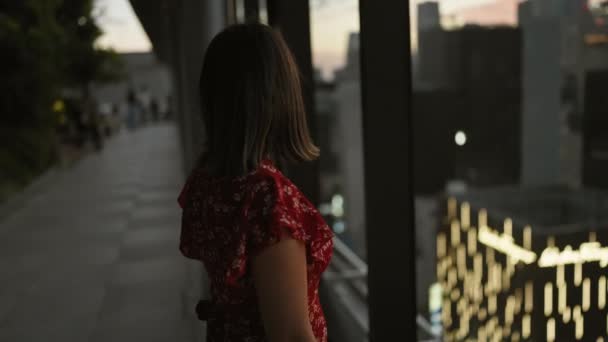 Usmívající se krásná hispánka v brýlích, sebevědomě se dívající z okna mrakodrapu na tokyo panorama, těší moderní japonský výhled na město - Záběry, video