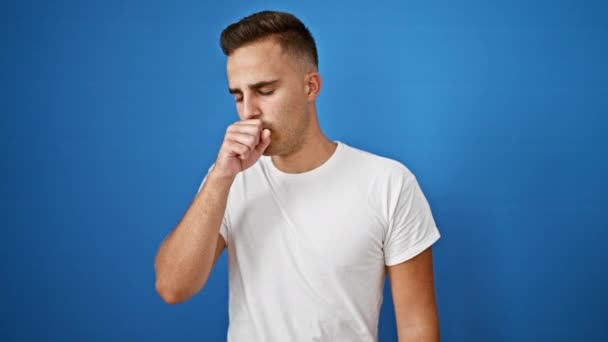 Молодой человек кашляет и плохо себя чувствует у голубой стены, изображая болезнь - Кадры, видео
