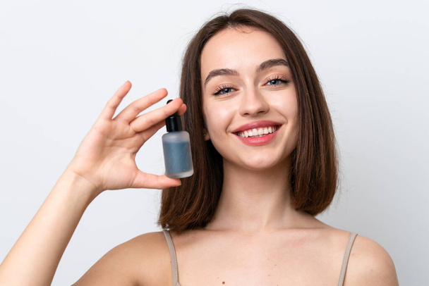 Young Ukrainian woman isolated on white background holding a serum while smiling. Close up portrait - 写真・画像