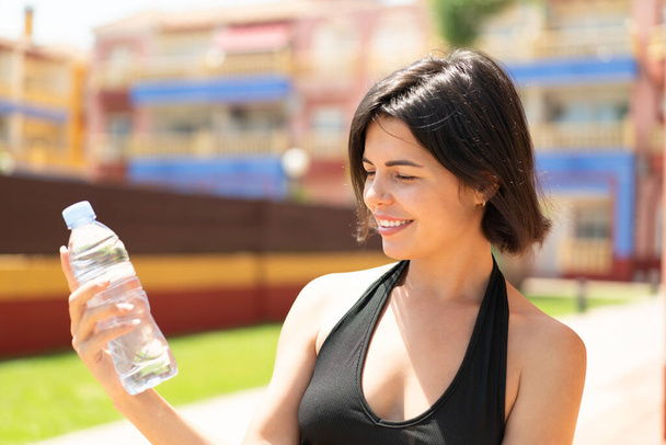 幸せな表情で屋外で水のボトルを持つ若いかわいいブルガリアの女性 - 写真・画像