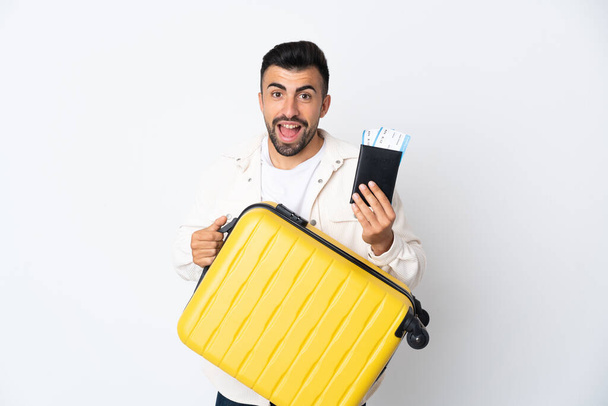 Hombre caucásico sobre fondo blanco aislado en vacaciones con maleta y pasaporte - Foto, Imagen