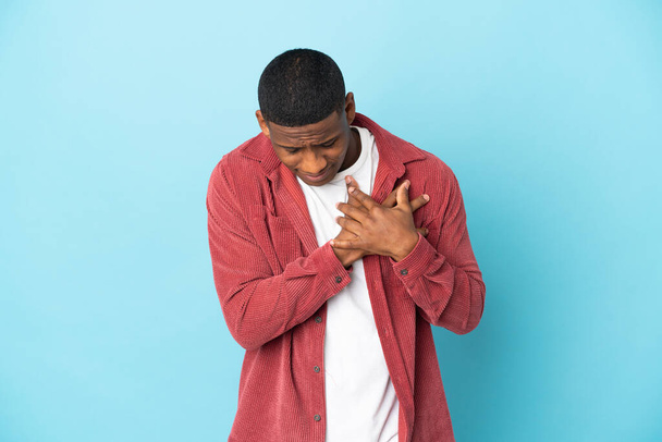 Νεαρός Λατίνος άνδρας απομονωμένος σε μπλε φόντο με πόνο στην καρδιά - Φωτογραφία, εικόνα