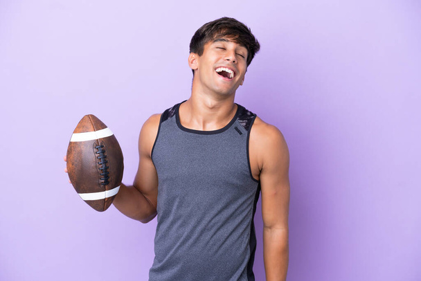 Young man playing rugby isolated on purple background laughing - Photo, Image