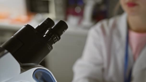 Científica enfocada usando microscopio en laboratorio - Metraje, vídeo