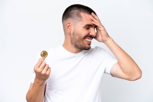 młody biały mężczyzna gospodarstwa bitcoin odizolowany na biały tło uśmiechając się dużo - Zdjęcie, obraz