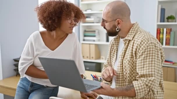 Впевнений чоловік і жінка партнери насолоджуються своєю роботою в офісі, посміхаючись, коли вони використовують ноутбук - Кадри, відео