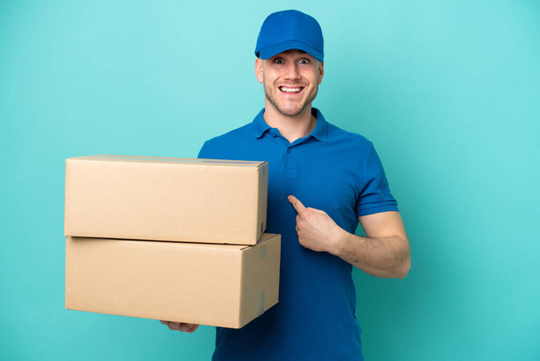 Delivery caucasian man isolated on blue background with surprise facial expression - Photo, Image