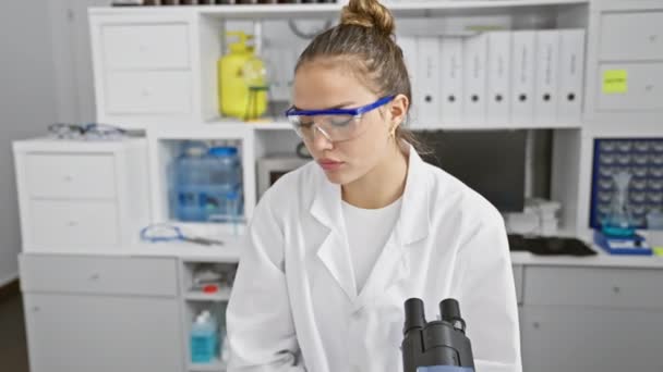Mosolygó fiatal női tudós, egy gyönyörű spanyol nő, aki a laborban dolgozik, szemüveget visel, örömmel átöleli az orvosi kutatást. - Felvétel, videó