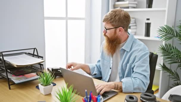 Gritty ír főnök, felnőtt vörös hajú férfi, elegánsan beszél telefonon, miközben dolgozik laptop irodai asztal, beltéri környezetben - Felvétel, videó