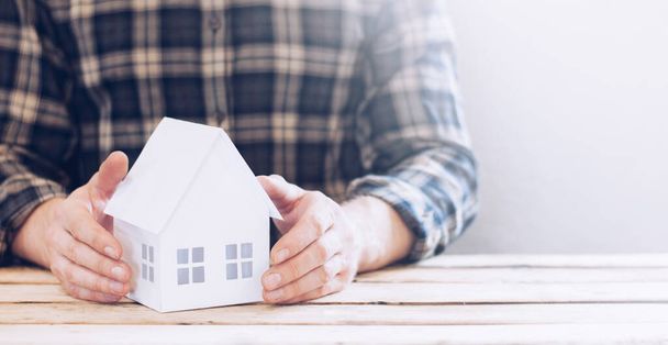 Miniature house project. Housing insurance. Loan for the purchase of a house. Home protection. A man holds a building in his hands. - Photo, Image