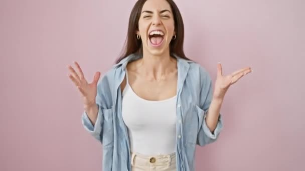 Fröhliche junge hispanische Frau in legerer Kleidung strahlt über den Sieg! feiert ihren Sieg mit einem strahlenden Lächeln und Siegerausdruck vor isoliertem rosa Hintergrund. - Filmmaterial, Video