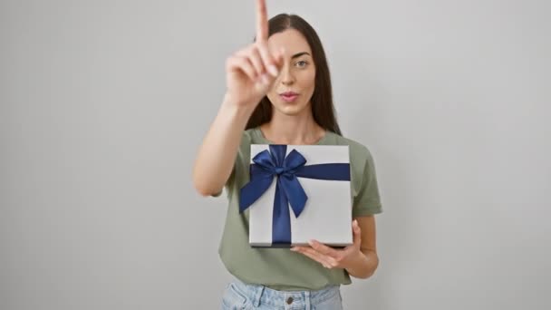 Confident young hispanic woman, holding a beautiful gift package, points at you. unwaveringly serious, she's got the energy of a leader, striding forth on a stark white backdrop. - Footage, Video