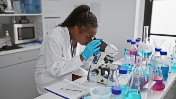専門の女性科学者は設備の整った実験室で顕微鏡を使用してサンプルを調べます. - 映像、動画