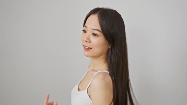 Junge asiatische Frau in weißem Tank-Top lächelt vor isoliertem weißen Hintergrund - Filmmaterial, Video