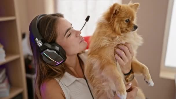 Usmívající se mladá hispánka streamer sdílení lásky pro hraní, vnitřní noční proud v tmavé místnosti, sebevědomý a šťastný se psem po jejím boku, pomocí herní sluchátka - Záběry, video